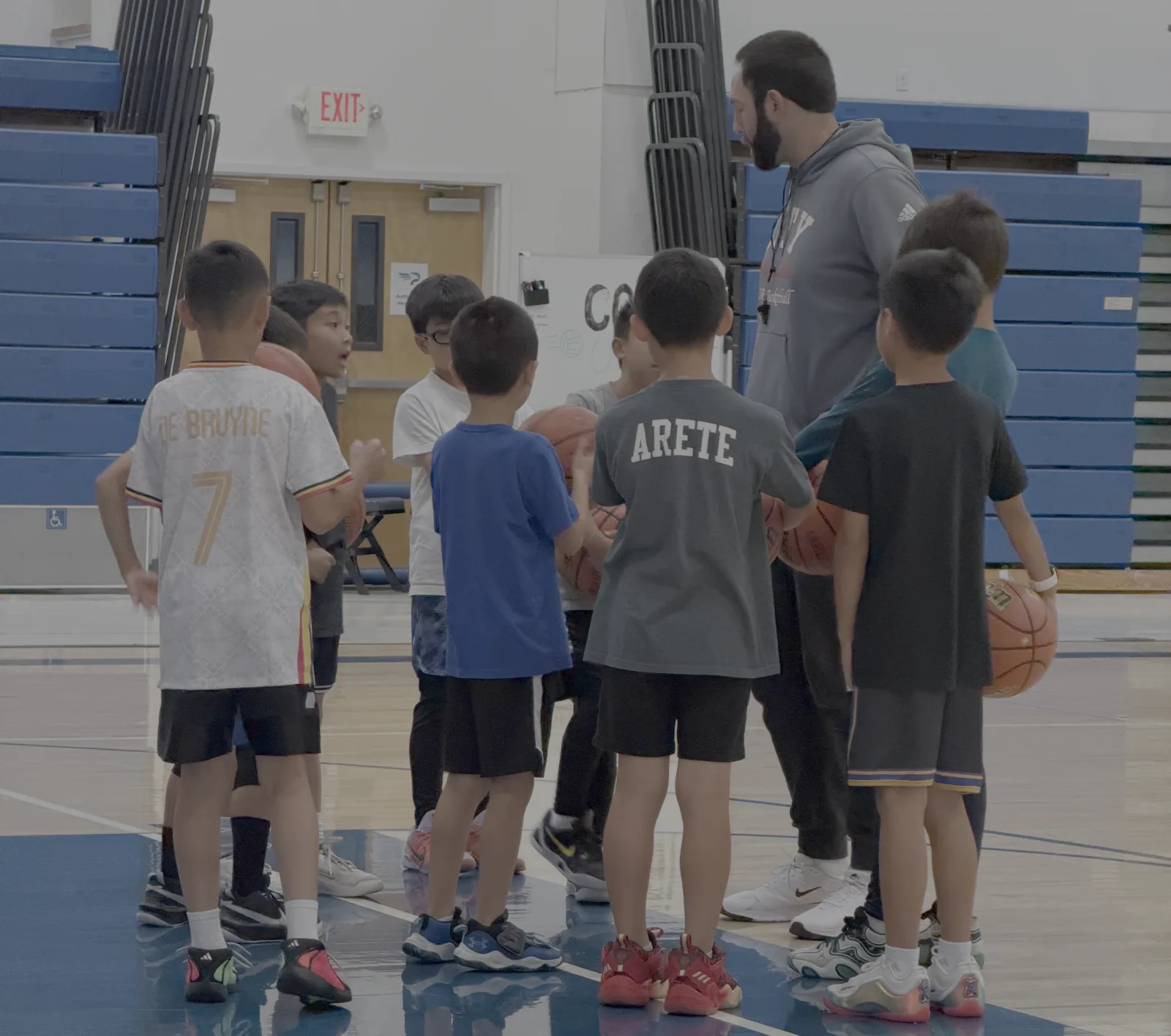 A youth basketball coach speaking with players gathered on the court